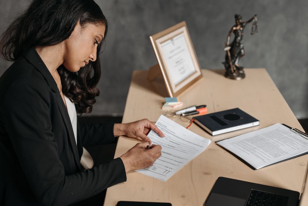 A lawyer or businesswoman reviews paperwork in an office setting.