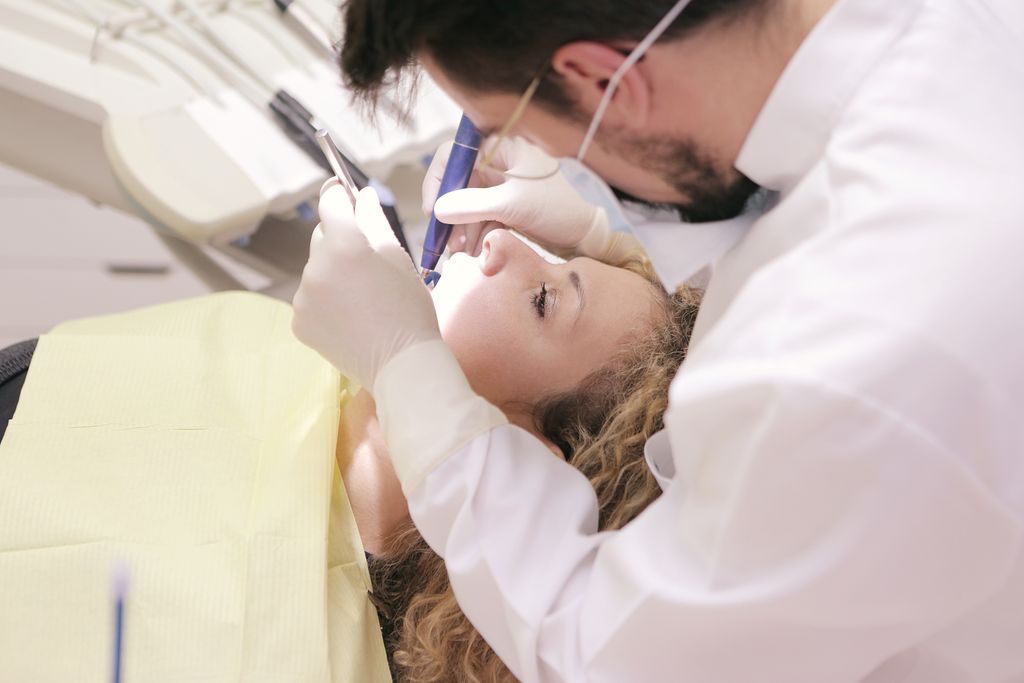 Dentist in clinic providing dental care to patient, focusing on oral health treatment.