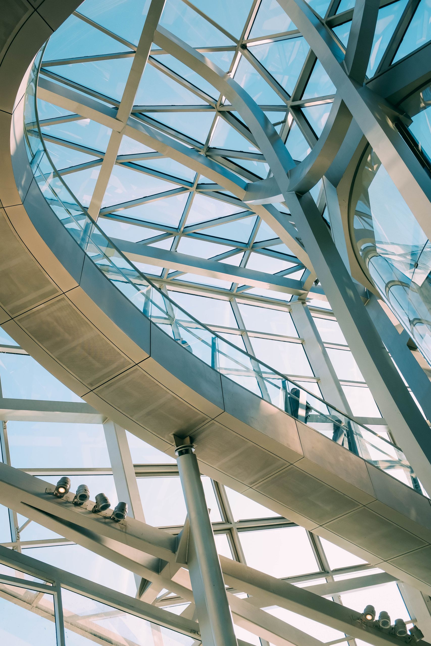 Modern glass and steel structure with geometric lines and daylight.