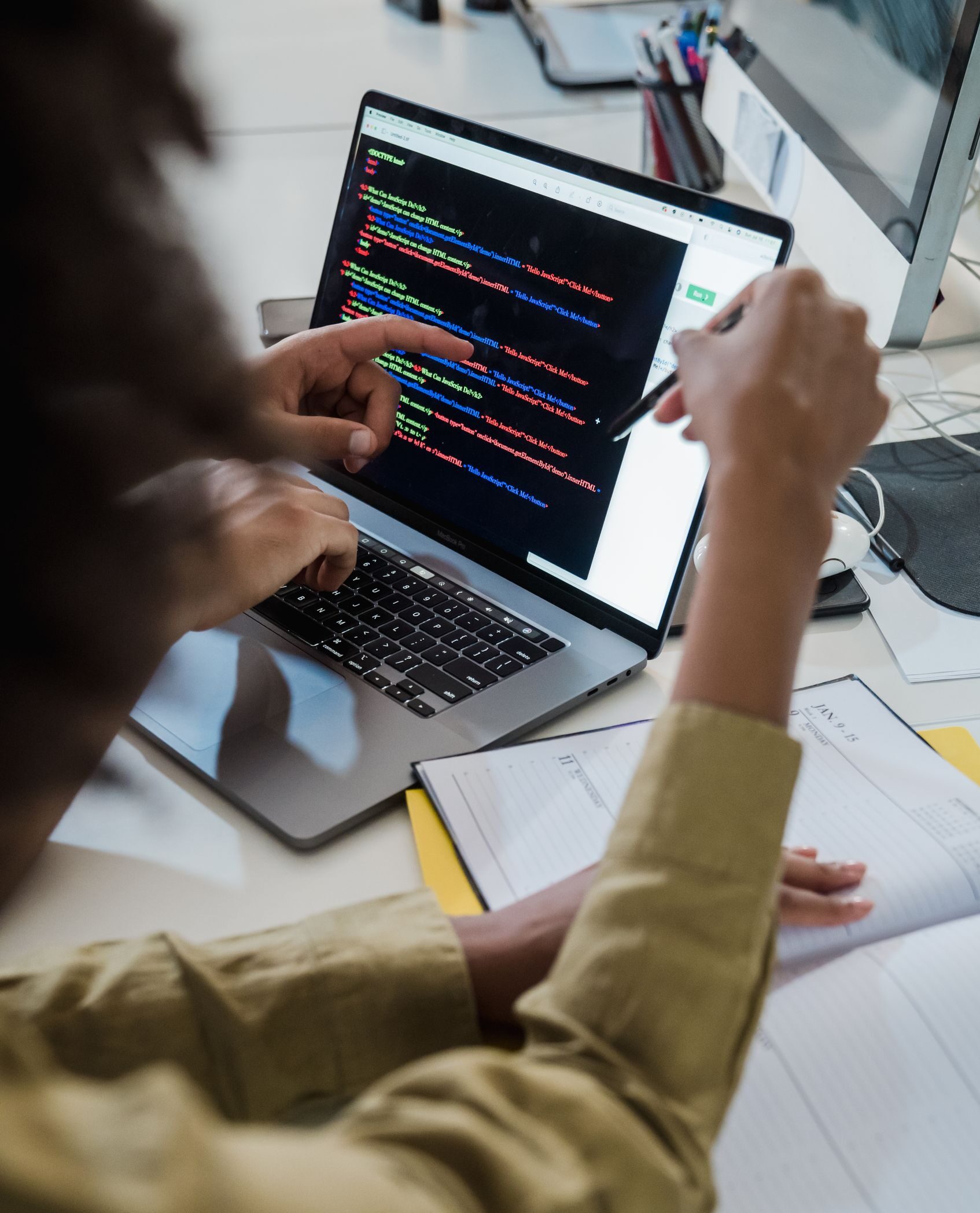 Two individuals discussing code on a laptop, focusing on web development.